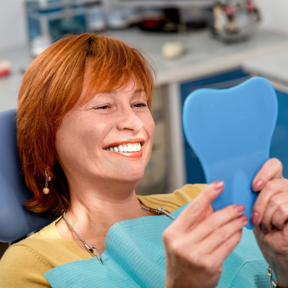 Woman in dentist chair smiling in a mirror